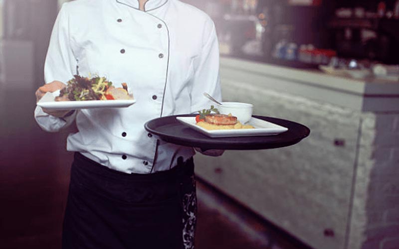 Image of a chef carrying plates of food