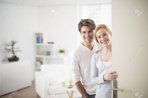 Image of Cheerful couple inviting people to enter in home