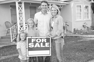 Image of family standing by for sale sign outside home