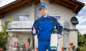 Smiling pest control expert standing in front of a house